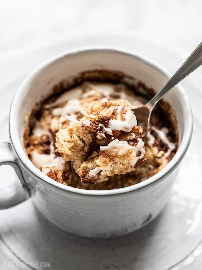 Front view of a spoon lifting a bite of Cinnamon Nut Swirl Mug Cake out of the mug.