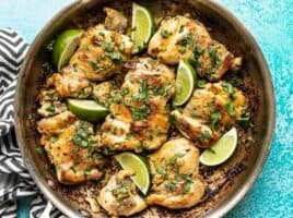 Close up of Easy Cilantro Lime Chicken in the skillet, garnished with cilantro and lime wedges.