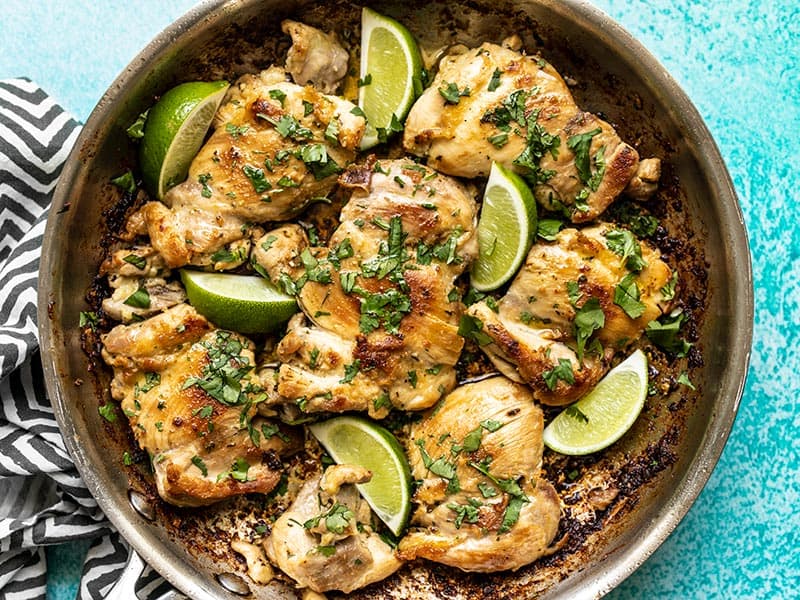 Close up of Easy Cilantro Lime Chicken in the skillet, garnished with cilantro and lime wedges.