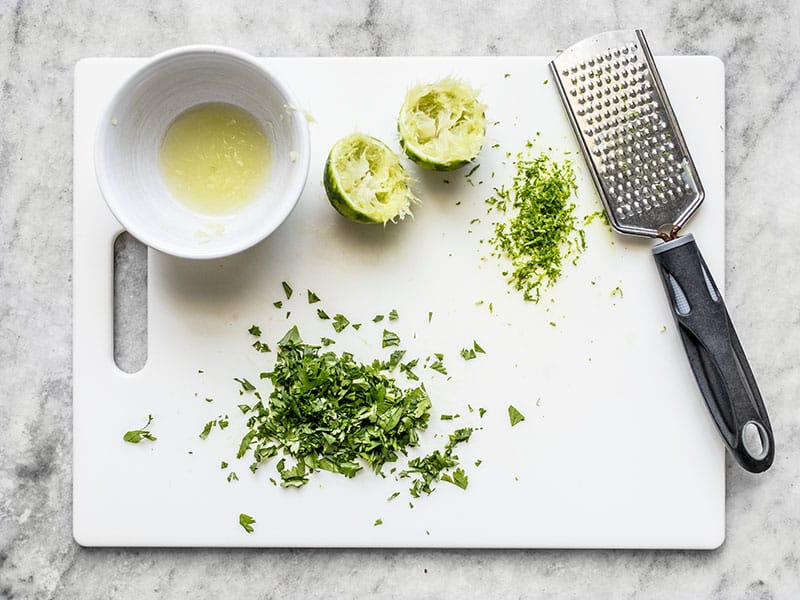 Juiced and Zested Lime and chopped cilantro on a cutting board