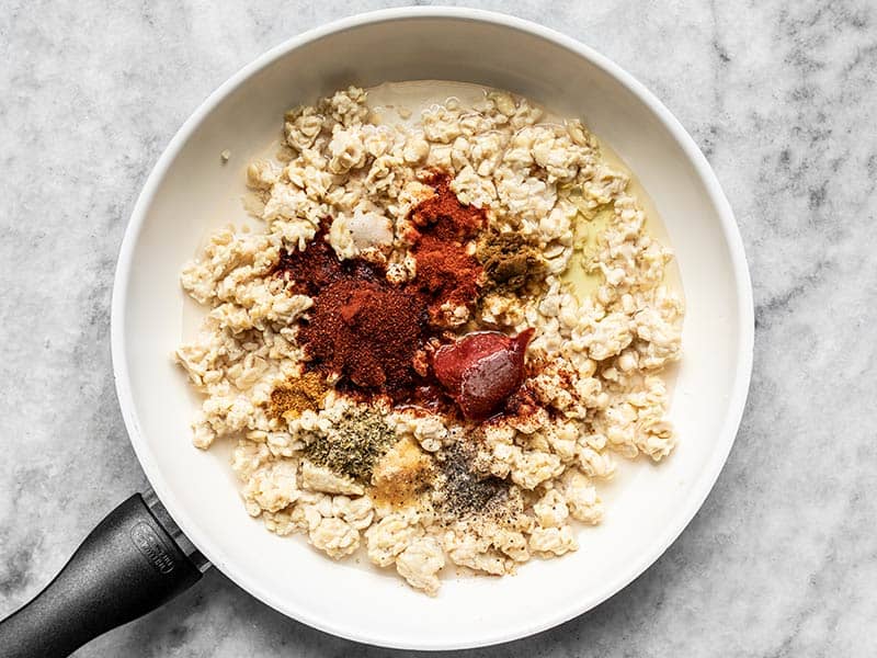 Spices tomato paste and water with tempeh in a skillet