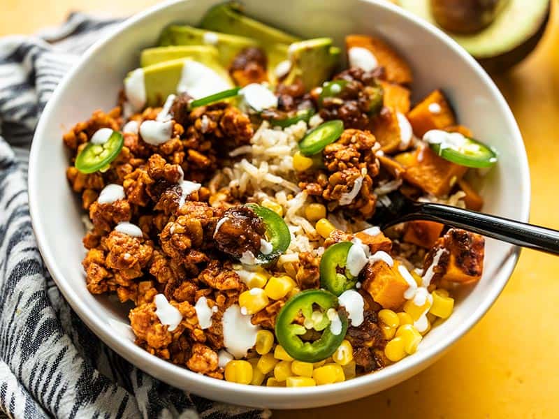 Close up front view of Tempeh Burrito Bowls with a fork scooping up a bite. 