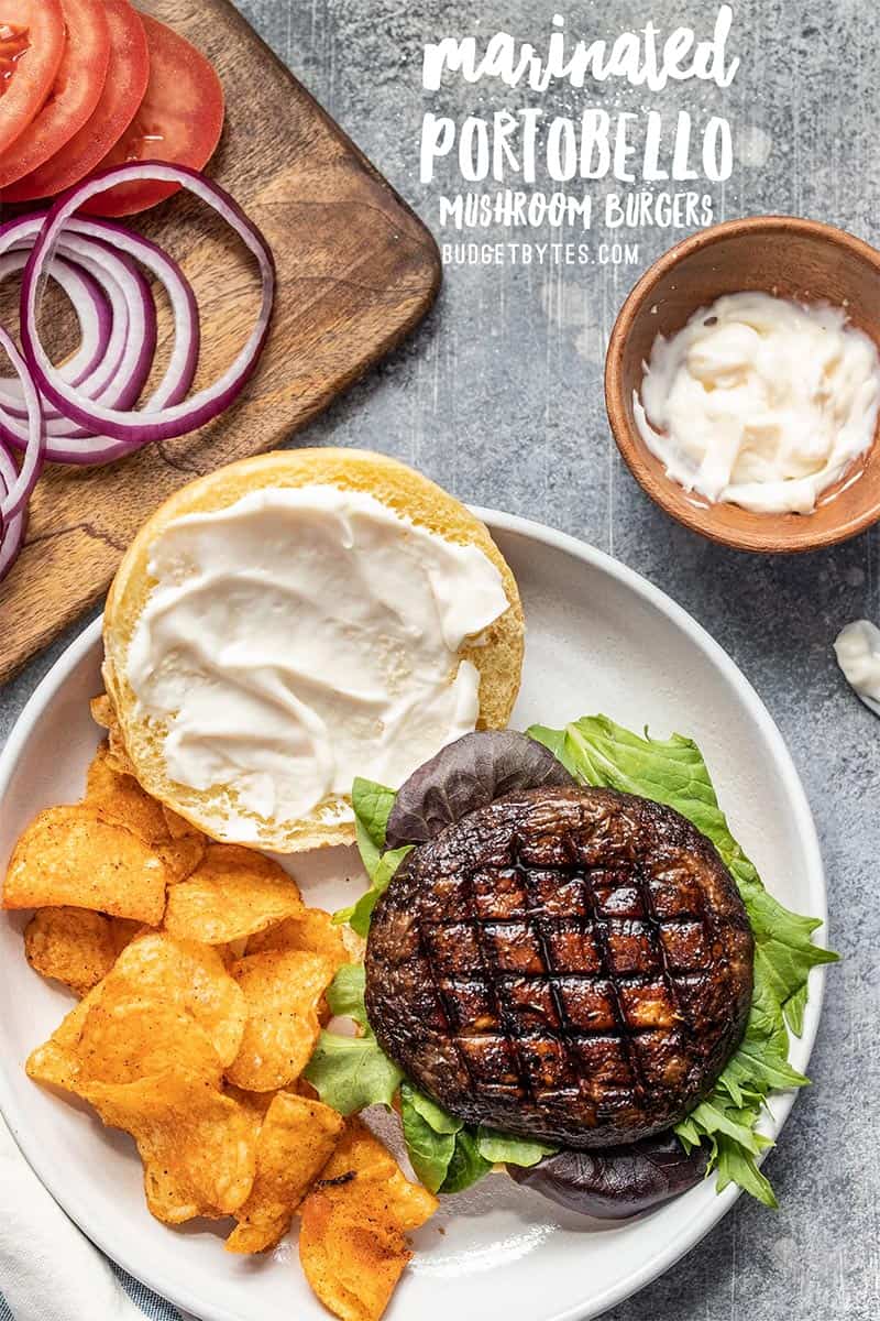 An open Marinated Portobello Mushroom Burger on a plate with chips, mayo and red onion rings on the side.