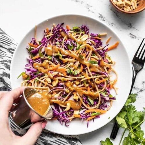 Peanut Lime Dressing being poured onto a bowl of Cold Peanut Noodle Salad