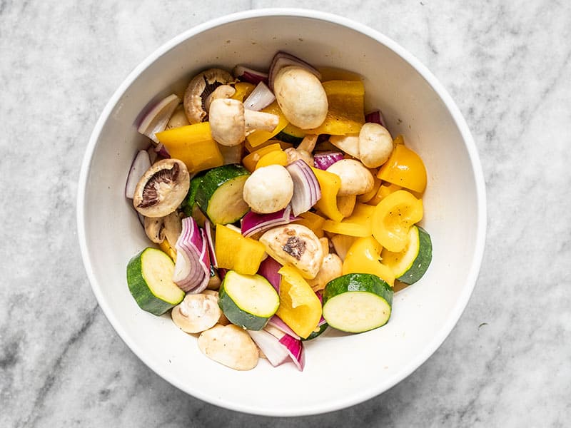 Diced vegetables coated in oil, salt, and pepper.