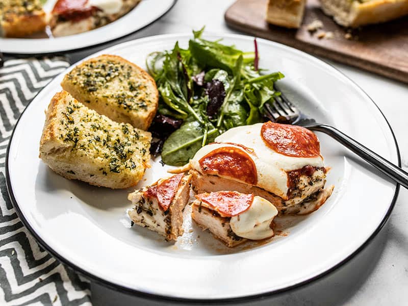 Front view of a piece of Baked Pizza Chicken cut into pieces on a plate.