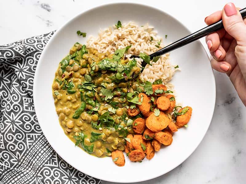 A forkful of Creamy Coconut Curry Lentils being lifted from the plate