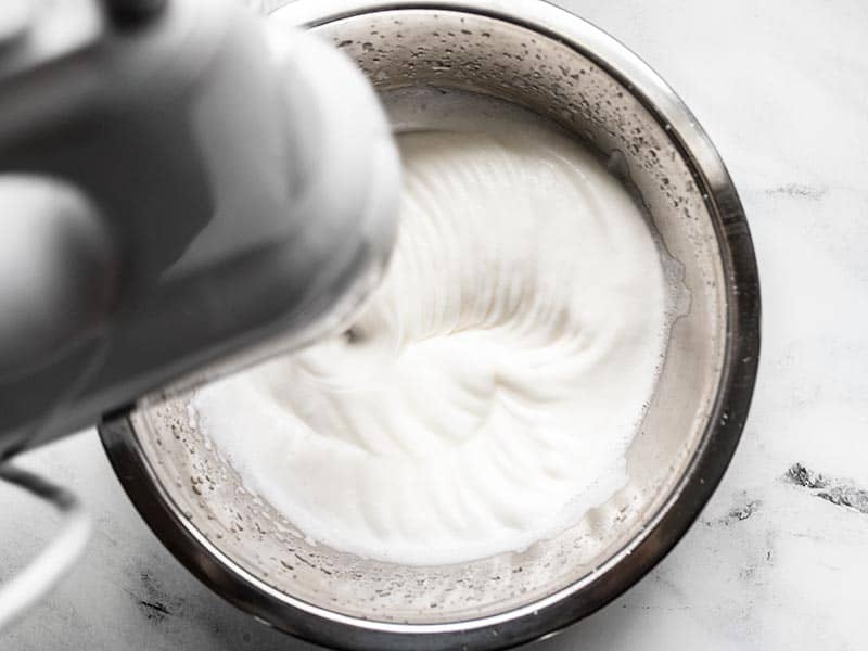 Whipped aquafaba in a bowl with a hand mixer