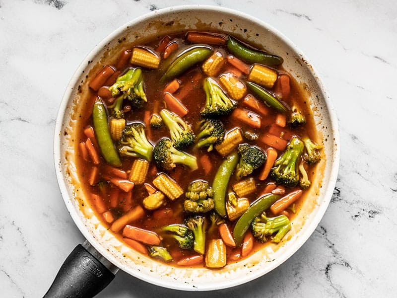 Cooked stir fry vegetables and sweet and sour sauce in the skillet