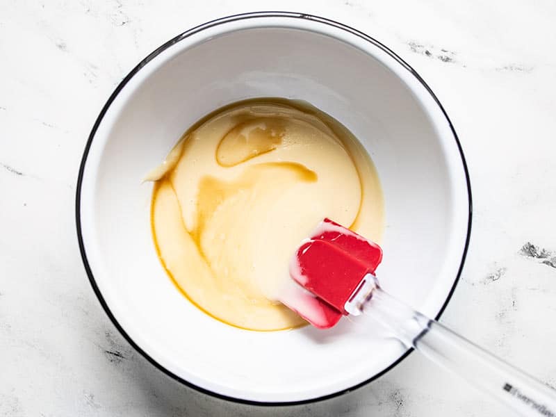 Sweetened condensed milk, vanilla, and salt being stirred together.