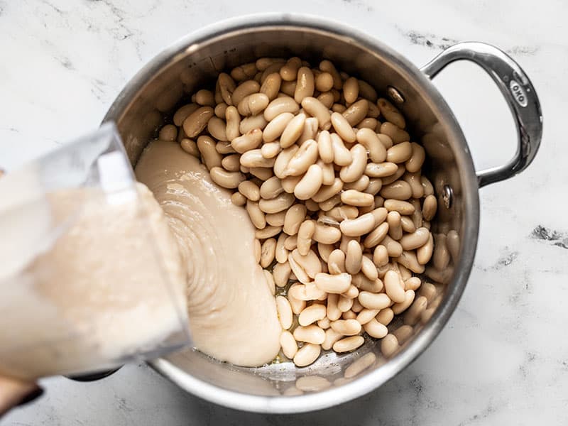 Add white beans (whole and pureed) to the soup pot