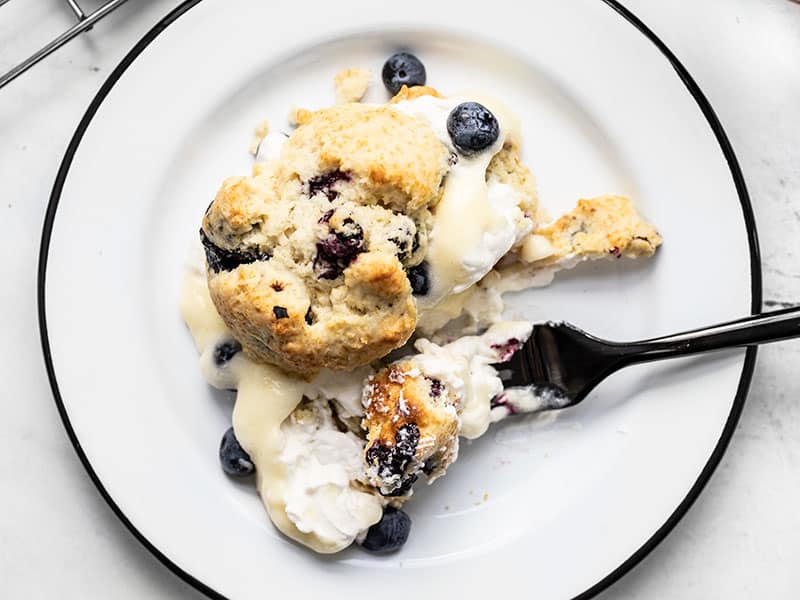 Close up of a Blueberry Lemon Curd Shortcake on a plate being eaten with a black fork