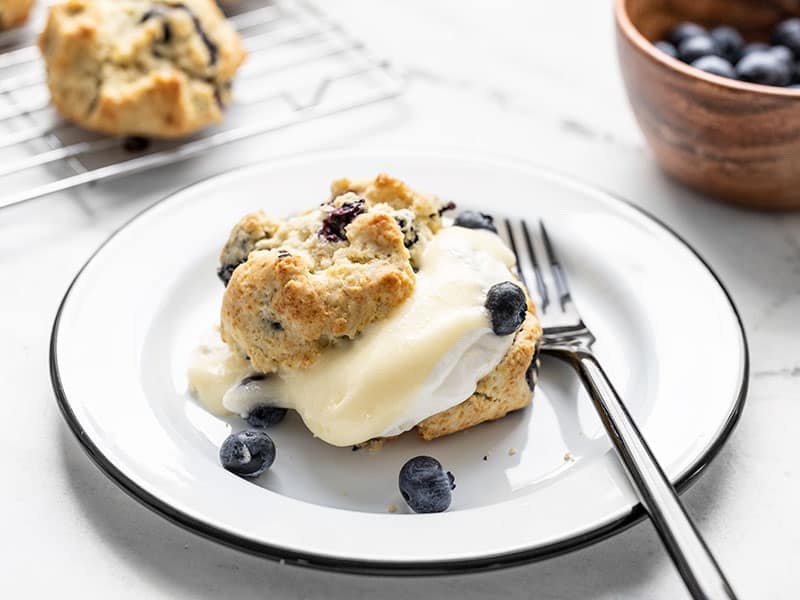 Side view of a Blueberry Lemon Curd Shortcake on a plate, bowl of blueberries in the back.