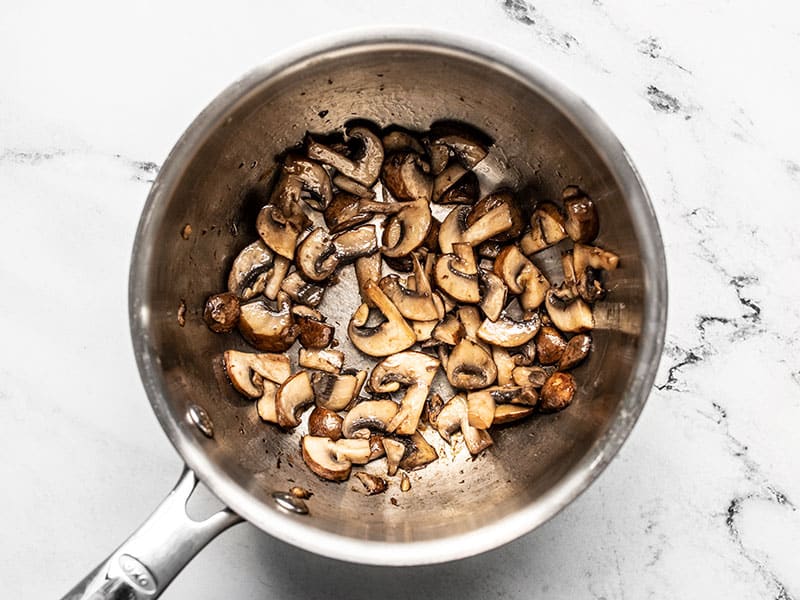 Cooked sliced mushrooms in a sauce pot