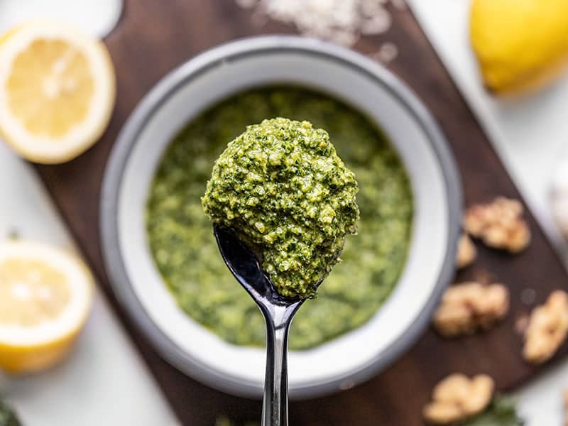 Close up of Kale Pesto on a spoon with the bowl in the background.