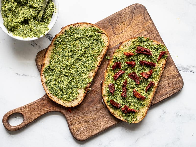 Sun dried tomato pieces added to pesto on bread.