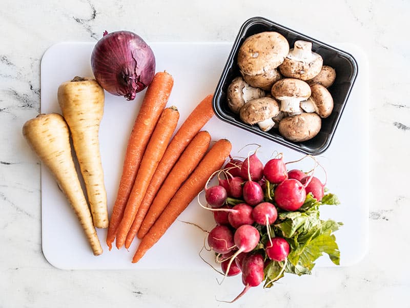 Whole vegetables for roasting on a cutting board