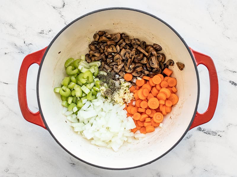 Onion, celery, carrots, garlic, and herbs added to the pot.