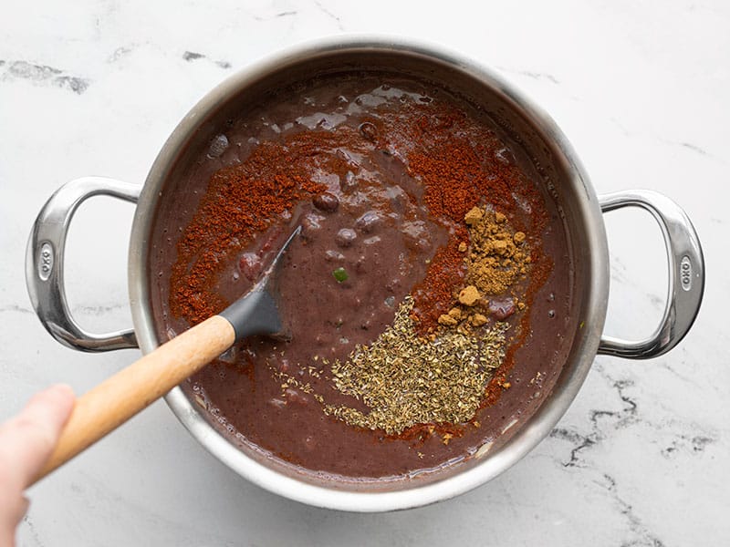 Spices being stirred into black bean soup