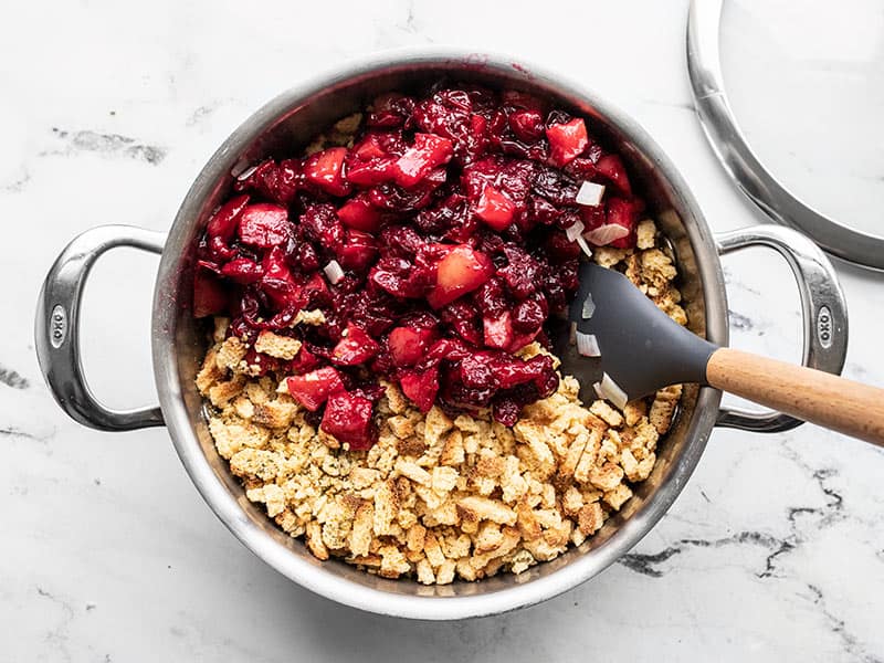 Roasted apples and cranberries being folded into the pot of stuffing