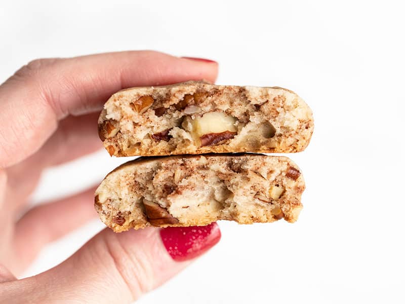 A cinnamon pecan sandie broken in half held close to the camera to show the inside texture.