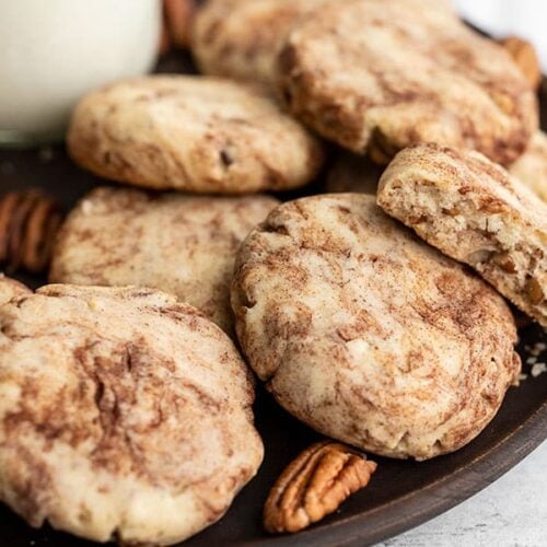 Close up of Cinnamon Pecan Sandies on a wooden plate with whole pecans