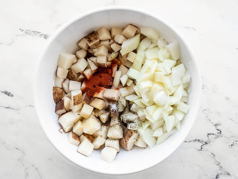 Potato, onion, and seasoning in a bowl