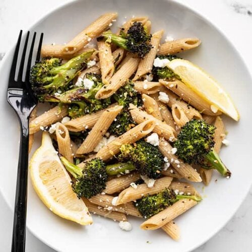 A bowl full of Roasted Broccoli Pasta with lemon and feta and a black fork on the left side