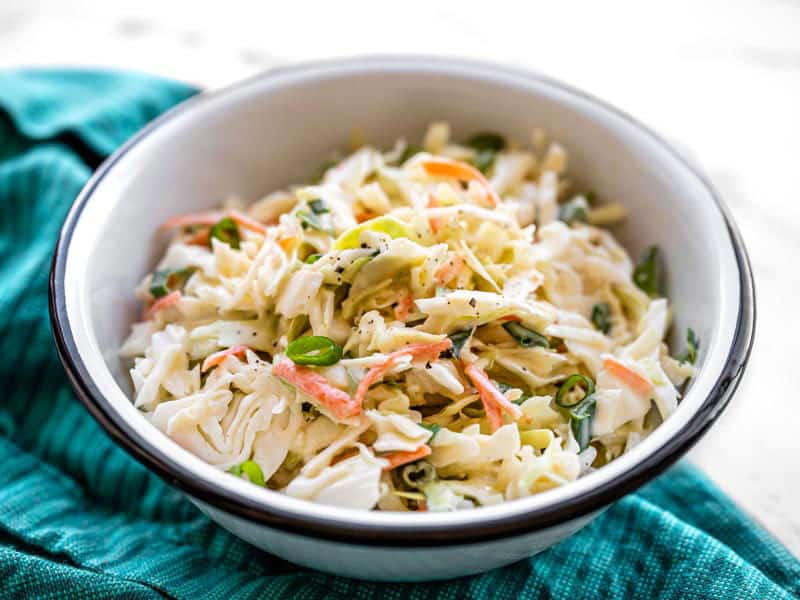 front view of a bowl of creamy coleslaw on a blue napkin