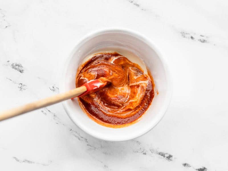 Sriracha mayo being stirred together in a small white bowl