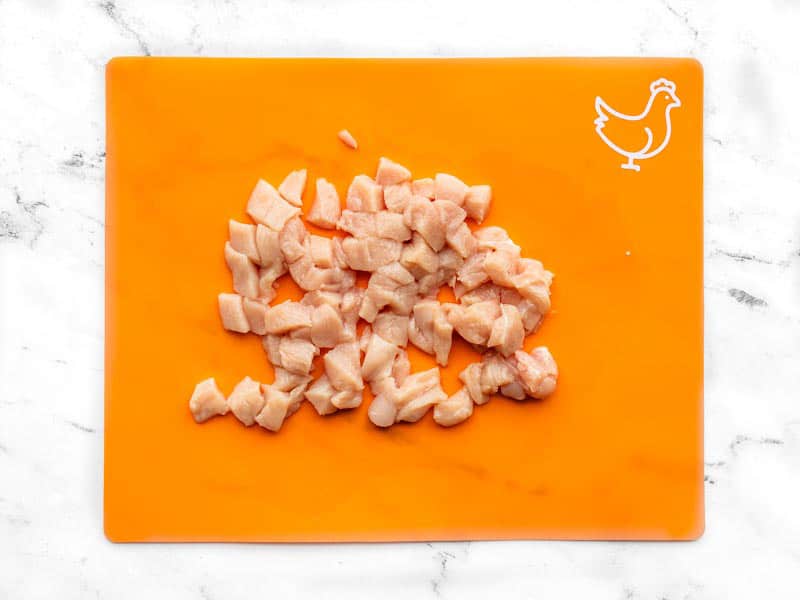 Chopped chicken breast on an orange cutting board