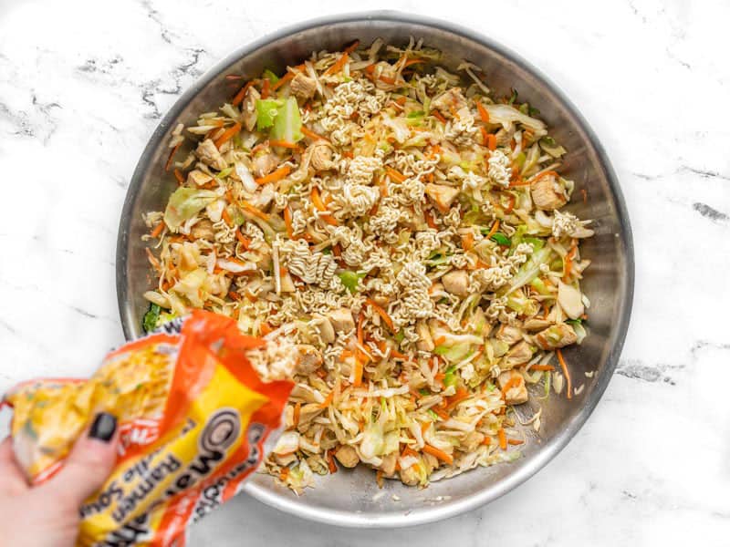 Crushed ramen noodles being added to skillet