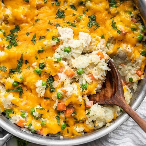 Close up of chicken and rice being scooped out of the skillet with a wooden spoon.