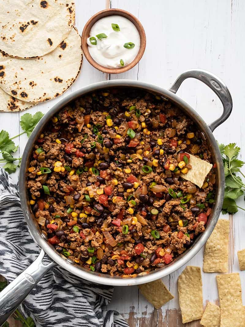 Turkey Taco Skillet next to tortilla chips, toasted corn tortillas, and a bowl of sour cream