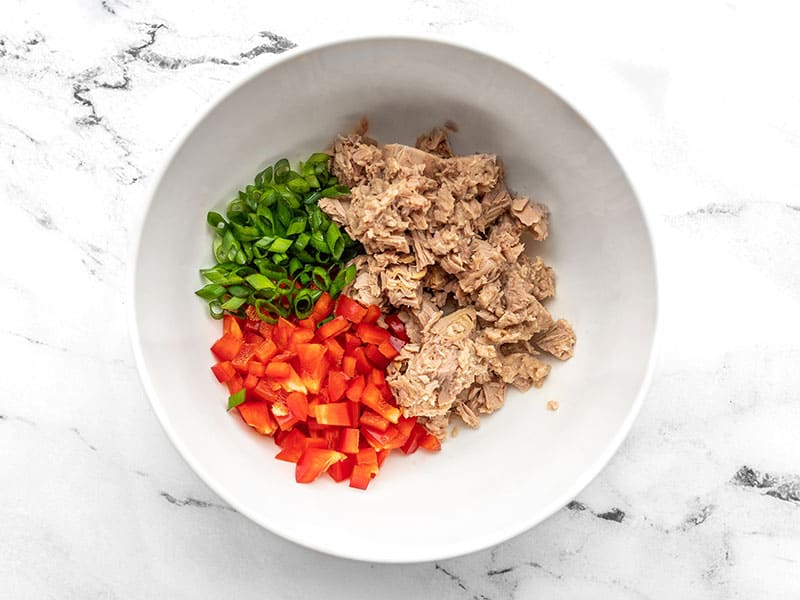 Tuna, diced red bell pepper, and sliced green onion in a bowl