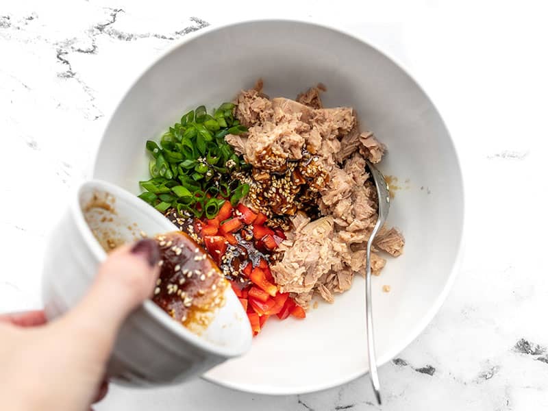 Sesame dressing being poured into the bowl with tuna