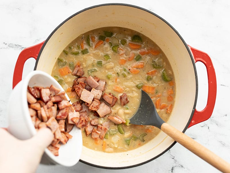 Cooked ham being poured back into the soup pot