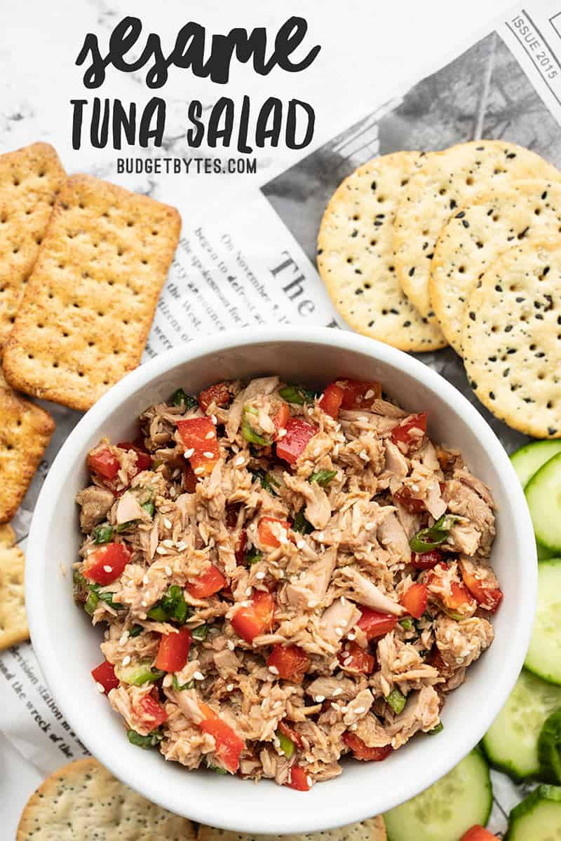 A bowl of sesame tuna salad surrounded by crackers and cucumber slices, title text at the top