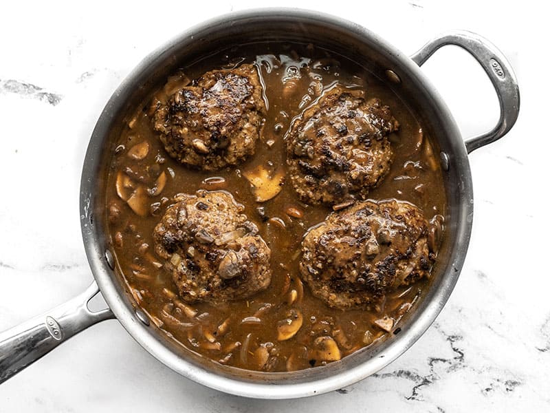 Simmered Salisbury Steaks in the skillet with mushroom gravy.