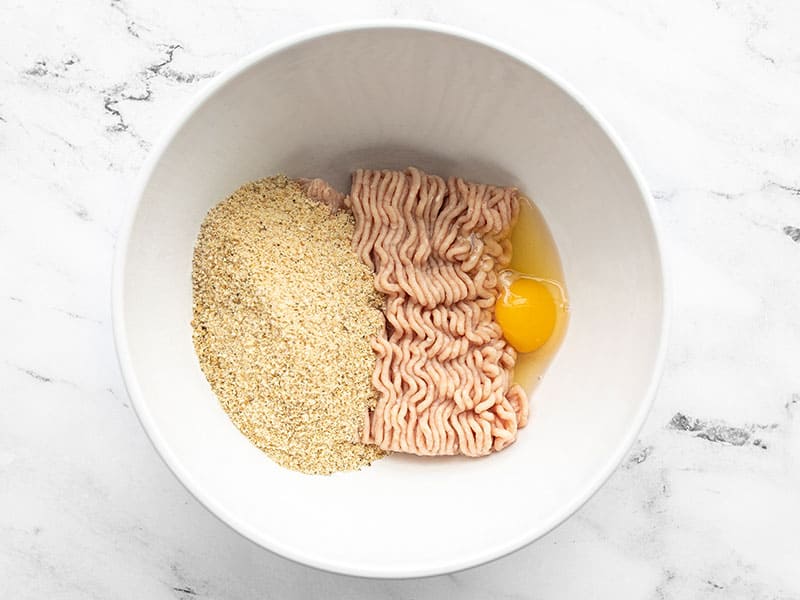 Ground chicken, egg, and seasoned breadcrumbs in a bowl