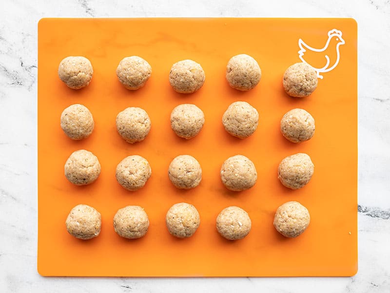 Shaped chicken meatballs on an orange plastic cutting board