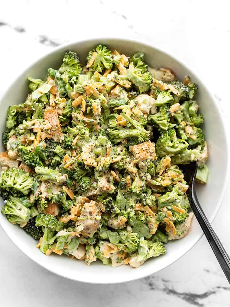 Overhead view of a large white bowl full of broccoli cheddar chicken salad with a fork