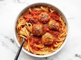 A bowl full of spaghetti with sauce and Chicken Parmesan Meatballs, with a fork in the side.