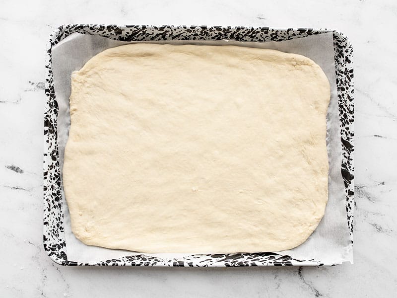 Pizza dough on sheet pan lined with parchment paper