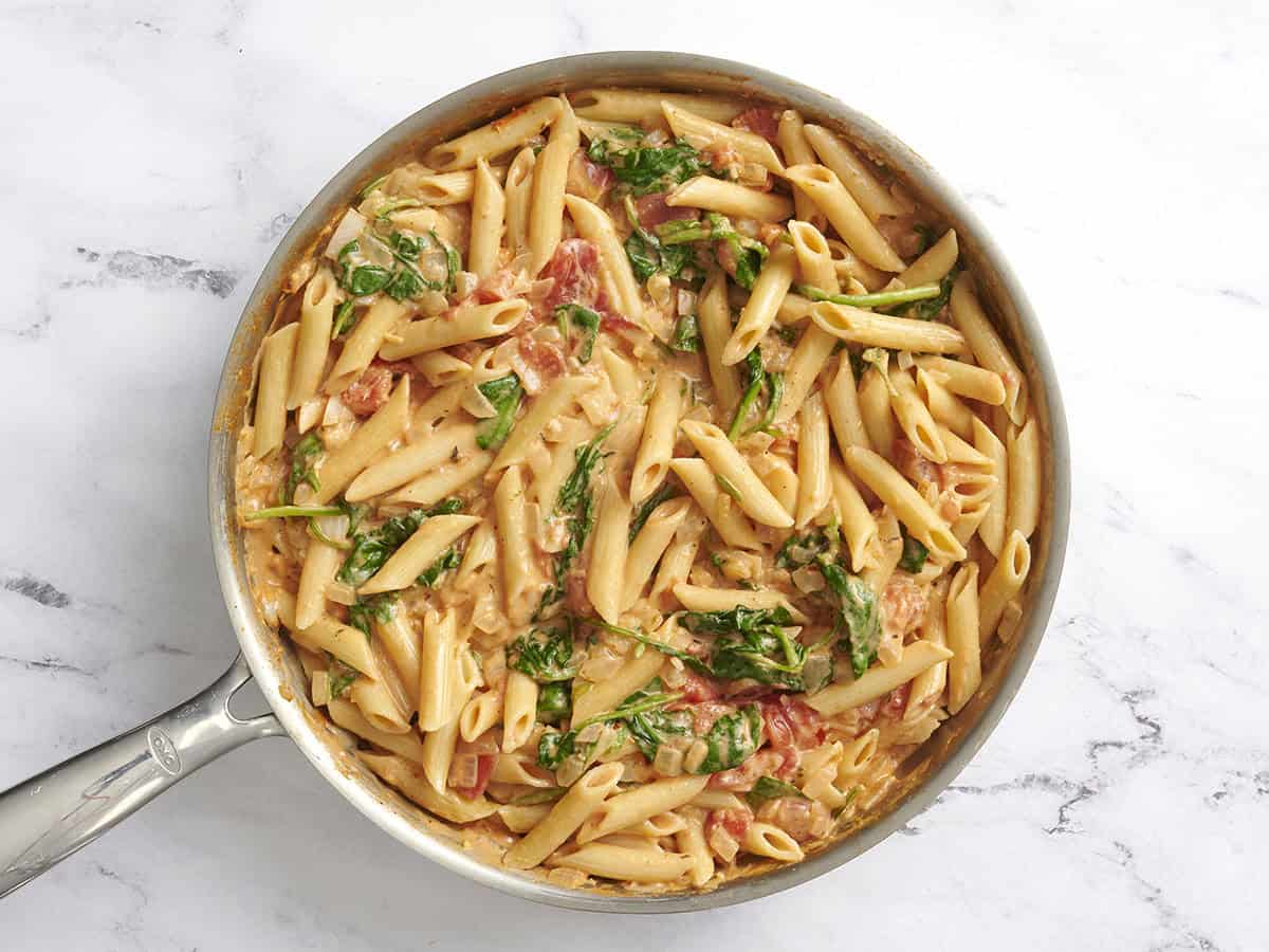 A skillet of creamy tomato and spinach pasta.