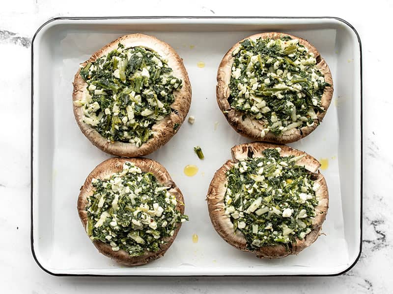 Portobello mushrooms stuffed but not baked, on a baking sheet