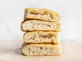 A stack of slices of no knead focaccia bread showing off large bubbles.