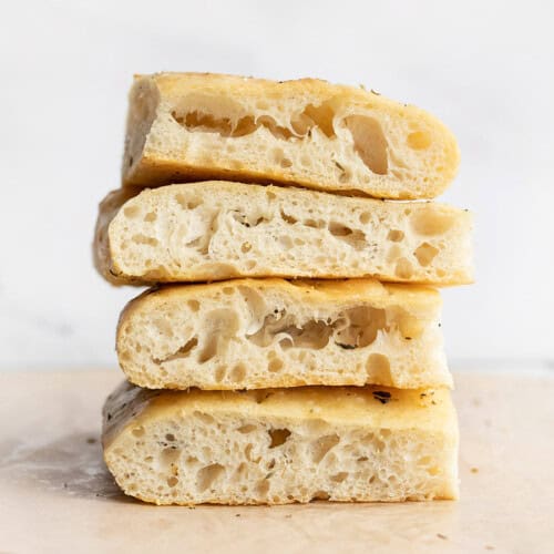 A stack of slices of no knead focaccia bread showing off large bubbles.