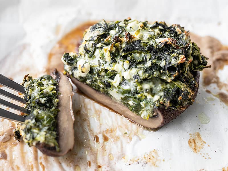 A spinach stuffed portobello mushroom cut open so you can see the inside