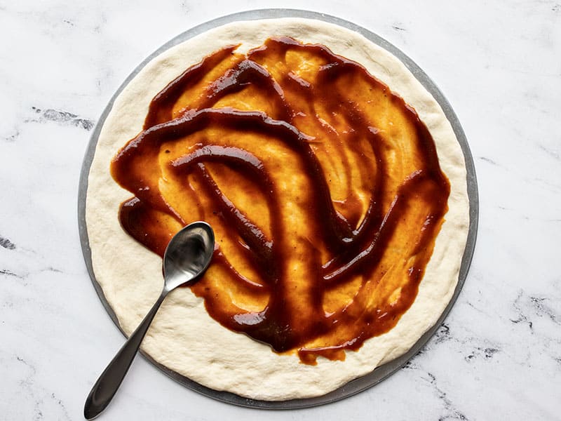 BBQ Sauce being spread on pizza dough